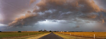 Dramatic Storm Clouds Over A Country Road And Flat Farmland