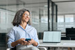 © insta_photos - Happy middle aged business woman holding phone looking away in office. Busy mature female professional employee using cellphone sitting at desk. Older businesswoman executive working on smartphone.