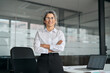 © insta_photos - Smiling mature female corporate leader, confident lady executive manager arms crossed looking at camera. Happy middle aged professional business woman wearing glasses standing in office, portrait.