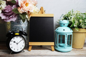 Poster - Easel mockup with blue landtern, alarm clock and flowers bouquet decoration on wooden background