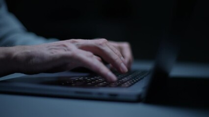 Detail cropped shot of unrecognizable hacker programmer working typing on keyboard laptop computer at dark room. Freelancer using laptop working from home, soft blue color. Shooing in slow motion.