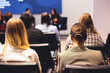 © tsuguliev - Female participants audience at the symposyum meeting, attendees in conference room hall listens to lecturer, group of women on a congress together listen to speaker on a stage at master-class