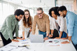 © Vadim Pastuh - Diverse colleagues gather around a laptop with bright expressions, indicating a successful collaborative effort and a lively brainstorming session in a well-lit, modern workspace, team work concept