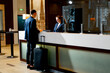 © Guys Who Shoot - The receptionist at the counter meets the guest with luggage in the hotel business travel hospitality