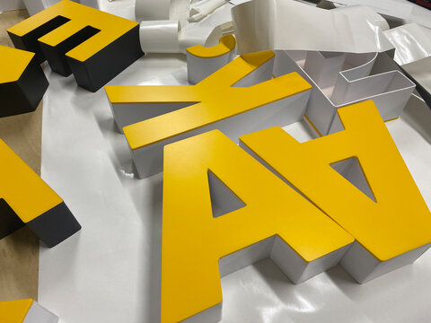Making letters from plastic to advertise the brand.Interior advertising in production. Letters made of PVC plastic are lying on the table.