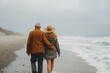 A couple stands hand in hand on a foggy beach, their clothing blending with the wintry sky as they brave the elements together in the embrace of nature