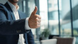 Businessman shows positive gesture thumb up in corporate setting