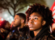 © apratim - Emotive image of a young African American woman with a poignant expression in a crowd at a nighttime event.