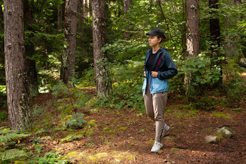 Autumn hike tourist lifestyle woman walking on trek trail in forest outdoors. Summer, autumn active girl with a backpack hiking outdoors.