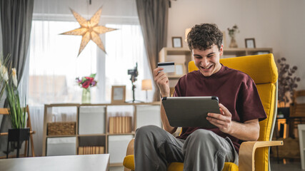 teenager young man sit at home use credit card shopping online