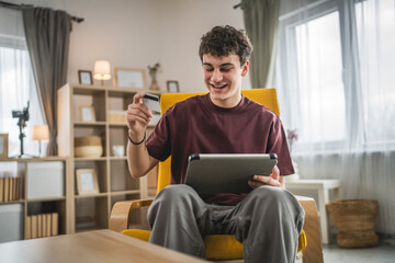 teenager young man sit at home use credit card shopping online