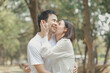 © kamiphotos - Happy young Asian couple in a park, Portrait of smiling couple near beautiful nature outdoors, lifestyle, Cheerful couple hugging each other, Young couple enjoying the sunny day at park