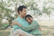 © kamiphotos - Happy young Asian couple in a park, Portrait of smiling couple near beautiful nature outdoors, lifestyle, Cheerful couple hugging each other, Young couple enjoying the sunny day at park