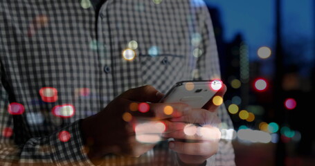 Poster - Spots of colorful bokeh lights against mid section of man using smartphone on the street