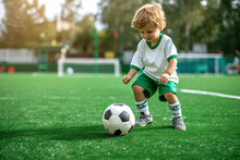 Cute Little Boy Playing Football On A Green Field.