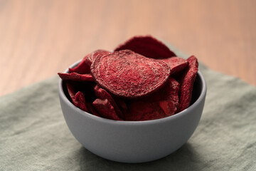 Wall Mural - Beetroot chips in ceramic bowl on wooden table with linen napkin