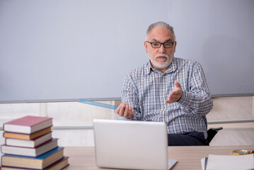 Wall Mural - Old male teacher in tele-education concept