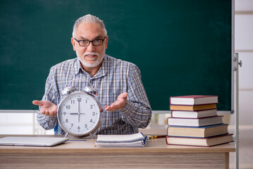 Wall Mural - Old male teacher in time management concept