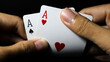 Closeup of a person hand holding a pair of aces against a dark background. Ideal for poker, blackjack, gambling, and casino concepts.