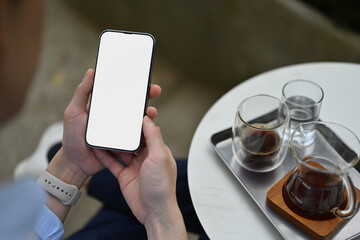 Poster - High-angle view of a businessman using a phone with an empty screen, relaxing with the coffee at outdoor cafe