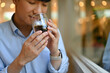 © saltdium - Cropped image with smart looking Young Asian man feeling refreshed by drinking and smelling a cup of coffee