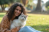 Fototapeta Panele - Smiling Young Woman Embracing Her Fluffy Tabby Cat Outdoors on a Sunny Day