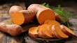 Organic sweet potatoes whole and sliced on wooden kitchen board. copy space for text.