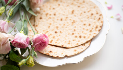 Wall Mural - Passover. Holiday of Jewish people. Traditional Matzo prepared for Passover decorate by flowers on white background. top view. Spring Holiday. Fasting time