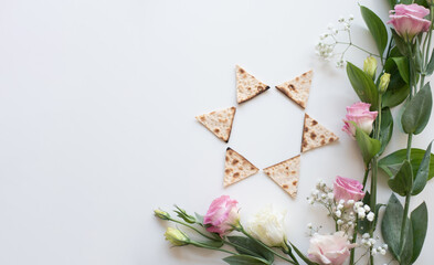 Wall Mural - Passover. banner of Traditional Matzo shape of star Magen David  decorate by pink flowers on white background. top view. Holiday of Jewish people, Spring Holiday. Fasting time