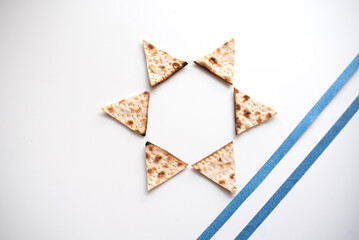 Wall Mural - Passover. banner of Traditional Matzo shape of six triangles star Magen David  decorate by two blue line  on white background. top view. Copy space for text. Holiday of Jewish people, Spring Holiday.