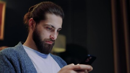Smiling man use smartphone dating app chatting internet browsing relaxing on couch at home apartment. Happy male social network communication texting message cyberspace searching information
