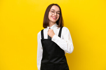 Wall Mural - Young Ukrainian waitress woman isolated on yellow background celebrating a victory