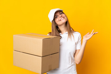 Young Slovak delivery woman isolated on yellow background extending hands to the side for inviting to come