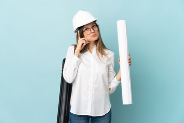 Slovak architect girl holding blueprints isolated on blue background thinking an idea