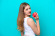 © luismolinero - Teenager Russian girl isolated on blue background eating an apple