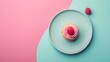 A raspberry cupcake with pink frosting on a blue plate against a pink and turquoise background