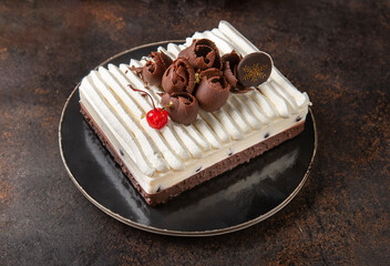 Chocolate pastry cake with cream and custard isolated in center on brown background