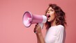 © liliyabatyrova - Close-up of a woman shouting into a white megaphone on a pink background. The concept of advertising with copy space for text.