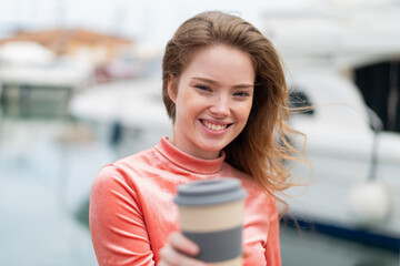 Sticker - Young redhead woman holding a take away coffee at outdoors with happy expression