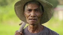 Genuine And Authentic Human Portrait Of Old Asian Farmer With Traditional Tool