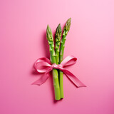 Fototapeta Tulipany - Bouquet of asparagus with a pink bow.Minimal creative food concept.Trendy social mockup or wallpaper with copy space.Top view,flat lay.Generative AI