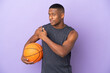 Young basketball latin player man isolated on purple background pointing back