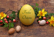 Grußkarte Frohe Ostern: Osterei mit dem Ostergruß Frohe Ostern beschriftet. Mit Wachteleiern und Blumen.