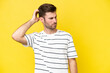 Young caucasian man isolated on yellow background having doubts while scratching head