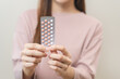 © KMPZZZ - Contraception and pregnancy, menstruation concept, birth control pills asian young woman hand holding hormonal oral contraceptive medicine, take pharmaceutical to prevention, safe virus sex disease.