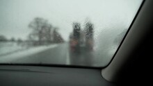 POV View From A Car While Driving In The Rain On A Snowy Road. A Car Overtakes A Large Truck With A Trailer. First-person View Passenger Traveling By Car On A Cloudy Spring Or Winter Day. Splashes