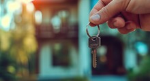 Key To Your New Home: Hand Holding Key With Copy Space On House Background