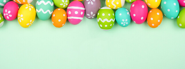 Poster - Colorful Easter Egg top border over a soft green paper banner background. Copy space.