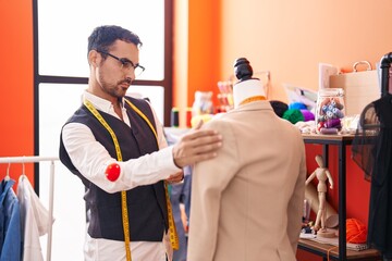 Canvas Print - Young hispanic man tailor drinking coffee standing by manikin at atelier