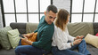 © Krakenimages.com - A couple sits closely on a couch, with the man peeking at the woman's phone in a modern living room setting.